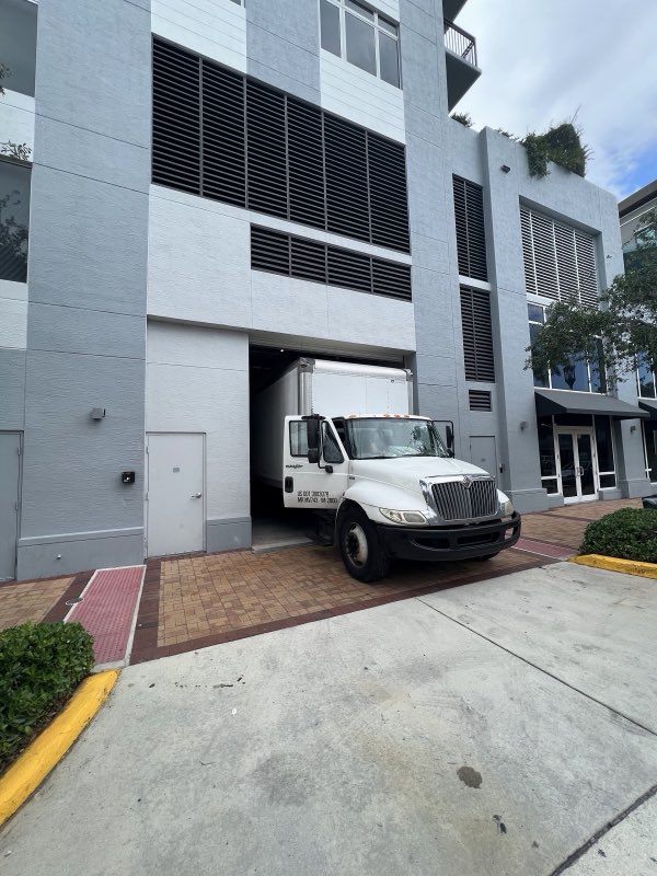 Florida Smart Moving box truck parked on site at a building loading area